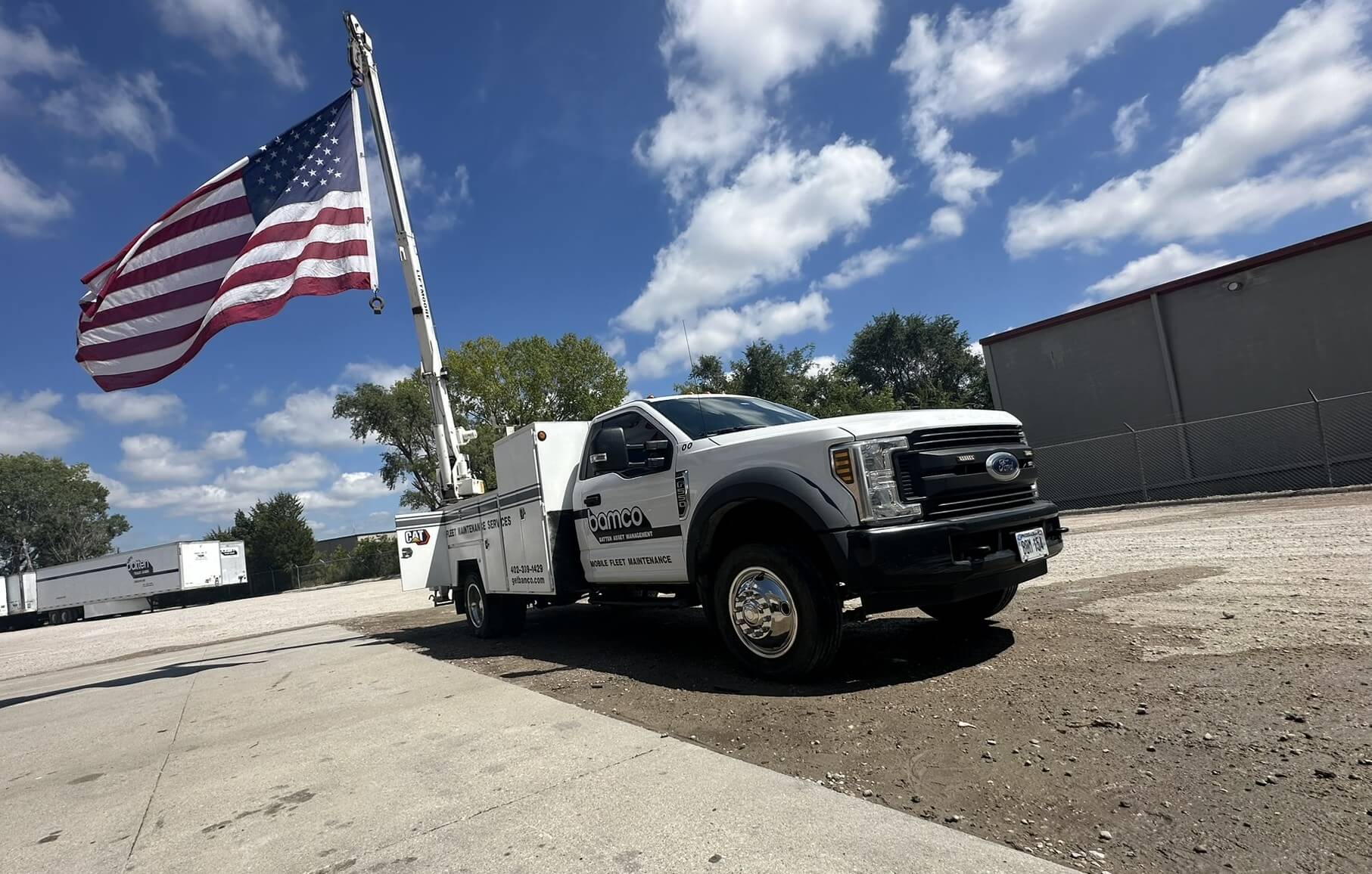 White Bamco truck with American flag attached to the back